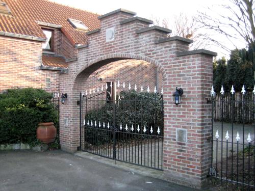 une clôture en briques avec une arche devant une maison dans l'établissement Hotel Plaza, à Lommel