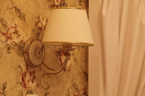 a lamp attached to a wall with a floral wallpaper at Régi Posta Hotel és Étterem in Debrecen