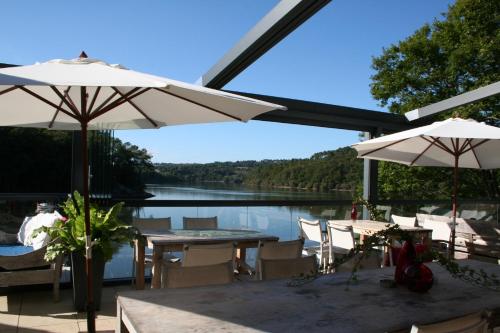 a patio with tables and umbrellas next to a lake at Merlin les pieds dans l'eau in Saint-Aignan