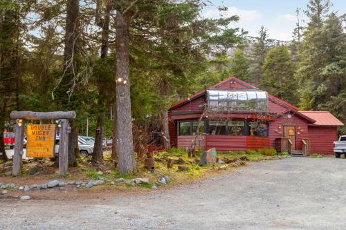 a red cabin in the woods with a tree at Crow Creek in Girdwood