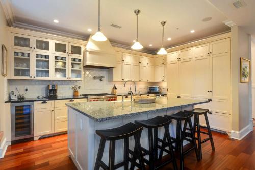 a kitchen with white cabinets and a large island with bar stools at 6002 Maritime Villa in Kiawah Island
