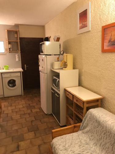 une petite cuisine avec un réfrigérateur et une table dans l'établissement Residence Courbet Meylouga, à Cauterets