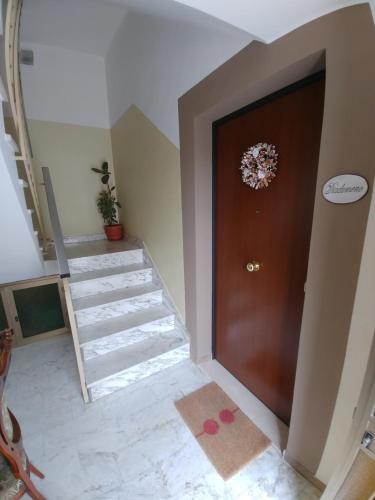 a hallway with a brown door and stairs at Diadumeno Superior Apartment in Venosa