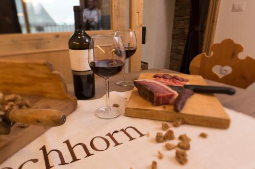 a bottle of wine and a glass of red wine and cheese at Landhof in Monguelfo