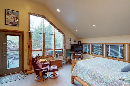 ein Schlafzimmer mit einem Bett und einem Schreibtisch sowie einige Fenster in der Unterkunft Crow Creek in Girdwood