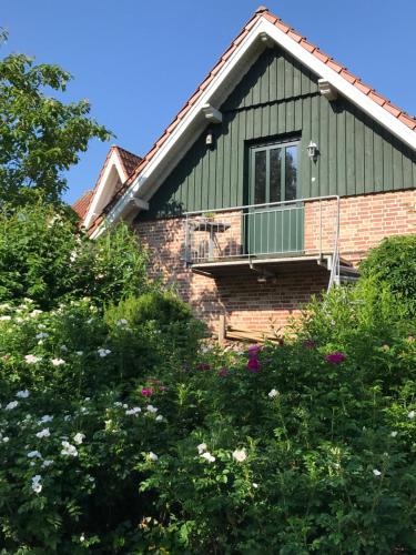 una casa verde con flores delante en Ferienwohnung Landart en Hilter