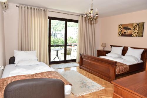 1 dormitorio con 2 camas, escritorio y ventana en Guest House Evropa, en Ulcinj