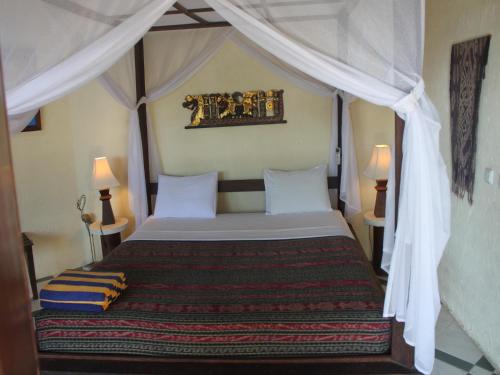 a bedroom with a bed with a canopy at Hotel Uyah Amed Spa Resort in Amed