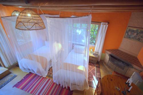 a room with a bed and a window with white curtains at Phophonyane Falls Ecolodge in Piggs Peak