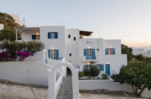 un edificio blanco con puertas y ventanas azules en Athena Rooms, en Ios Chora