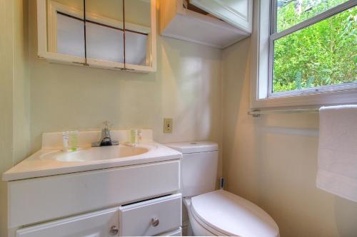 baño con aseo y lavabo y ventana en Downtown Cottage in the Woods, en Guerneville