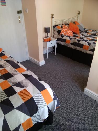 a bedroom with two beds and a table with a lamp at The Castleton in Blackpool