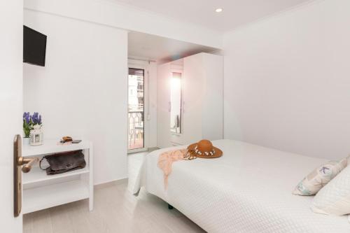 a white bedroom with a bed and a television at Ericeira T1 Navegantes Apartment in Ericeira