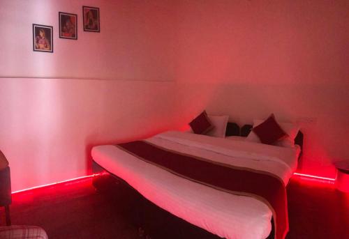 Un dormitorio con una cama con luces rojas. en Hotel Dharohar Palace en Jaipur