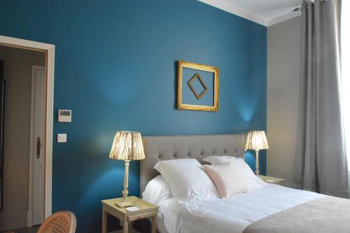 1 dormitorio con una pared azul, 1 cama y 2 lámparas en Villa Vesone en Périgueux