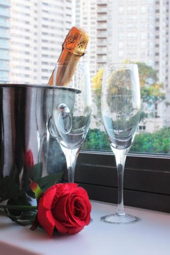 two wine glasses and a rose on a window sill at Residence Master Suite en Porteño Building in Buenos Aires