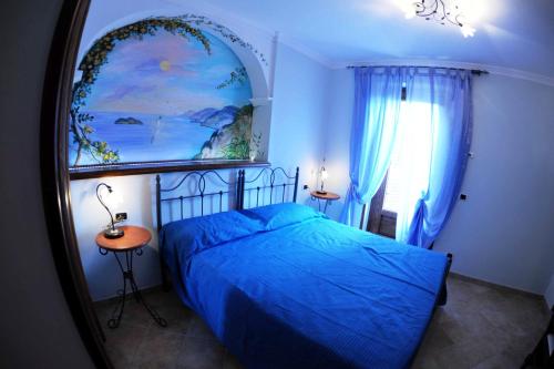 a bedroom with a blue bed and a painting on the wall at B&B Miramare in Agerola