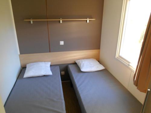 deux lits dans une petite pièce avec une fenêtre dans l'établissement Camping les Borgnes Saint-Sozy, à Saint-Sozy