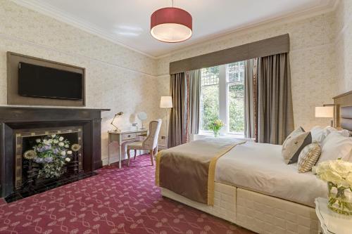 a hotel room with a large bed and a fireplace at Burn How Garden House Hotel in Bowness-on-Windermere
