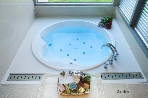 a bath tub in a bathroom with a sink at Comma&Spa Resort in Seogwipo