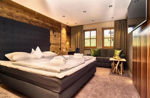 a bedroom with a large bed and a couch at Zedernhof Gesundheits- & Wellnesshotel in Stamsried