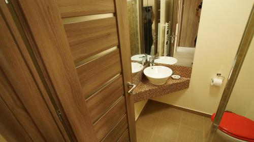 Un baño con puerta de madera y lavabo. en Vila Fara Nume, en Mamaia Nord – Năvodari