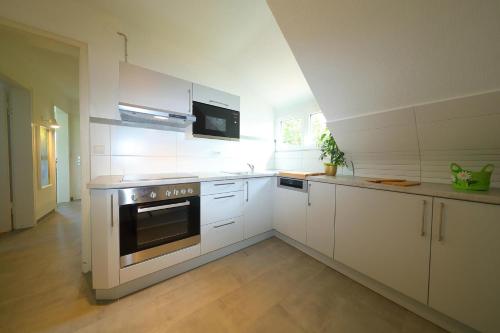 a kitchen with white cabinets and a stove top oven at Ferienwohnung Biermann in Aspach