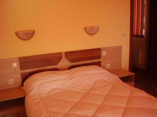a bedroom with a white bed with a wooden headboard at Guest House Goranovi in Velingrad