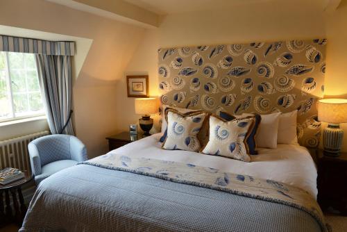 um quarto com uma cama grande e uma cadeira azul em The Manor House Hotel em Moreton-in-Marsh