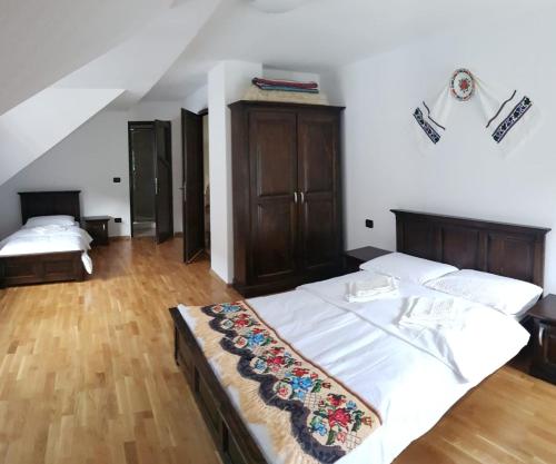 a bedroom with two beds with white sheets and wooden floors at CASA Fratii MÂT in Moisei
