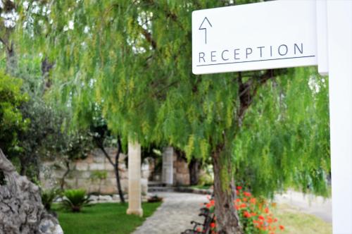a white sign that says reception next to a tree at Masseria Torrepietra in Monopoli