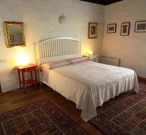 1 dormitorio con 1 cama blanca, 2 mesas y espejo en Antico Borgo Camporeso, en Galbiate