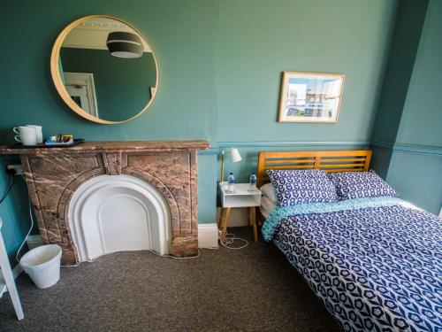 a bedroom with a bed with a fireplace and a mirror at Westward Ho Hotel in Folkestone