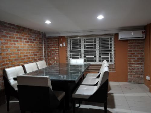 a dining room with a glass table and white chairs at Kenyalang Urban Homestay in Kuching