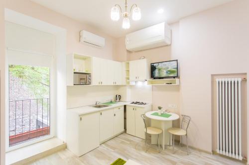 a kitchen with white cabinets and a table and a window at Basseynaya Apart Hotel in Kyiv