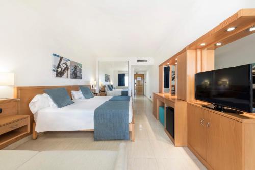 a hotel room with a bed and a flat screen tv at Ukino Palmeiras Village - 24h All Inclusive in Armação de Pêra