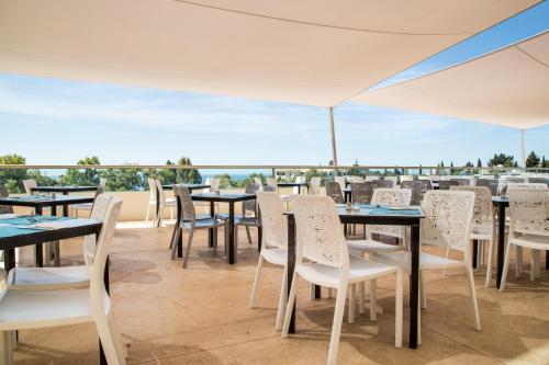 a restaurant with tables and chairs and a view of the ocean at Ukino Palmeiras Village - 24h All Inclusive in Armação de Pêra