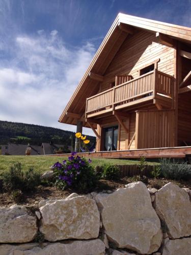 a log cabin with a balcony and a stone wall at Au cœur du bois in Le Bouilly