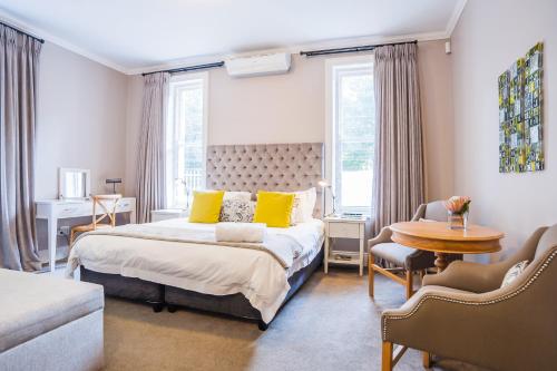 a bedroom with a bed with yellow pillows and a table at Bonne Esperance Studio Apartments in Stellenbosch