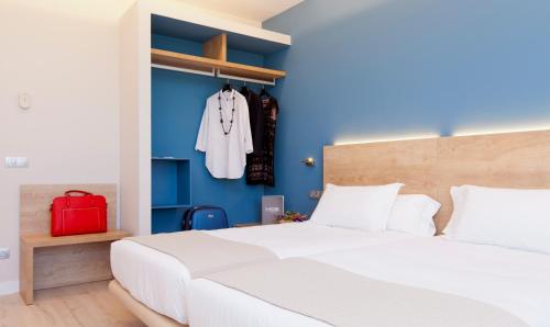 a bedroom with a white bed and a red suitcase at Spirit Hotel Ciudad de Burgos in Rubena