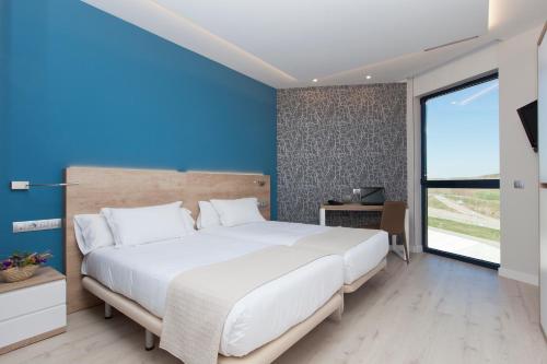 a bedroom with a large white bed and a blue wall at Spirit Hotel Ciudad de Burgos in Rubena