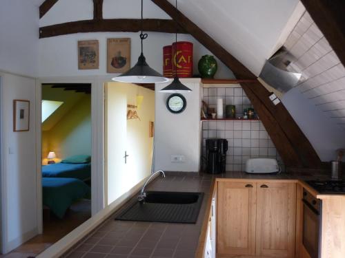 eine Küche mit einem Waschbecken und einer Uhr an der Wand in der Unterkunft Gîte La Borie Basse in Léobard