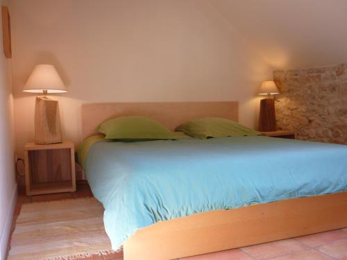 une chambre avec un grand lit avec des oreillers verts dans l'établissement Gîte La Borie Basse, à Léobard