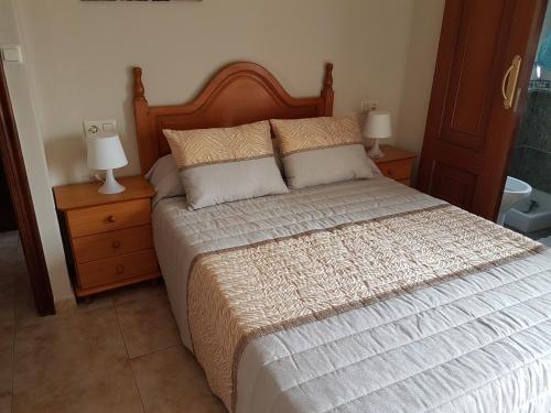 a bedroom with a bed with two night stands and two lamps at Hogar del Puerto in Combarro