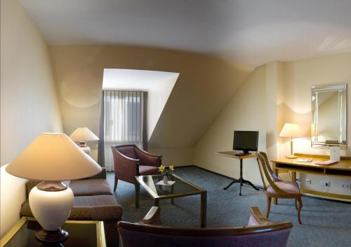 a hotel room with a couch and chairs and a desk at Galerie Hotel Leipziger Hof in Leipzig