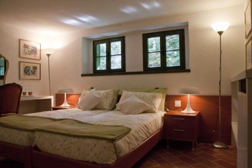um quarto com uma cama com 2 candeeiros e 2 janelas em Il giardino di Raffaella em Montorfano