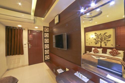 a room with a bed and a tv on a wall at Hotel Grand Pragati in Surat