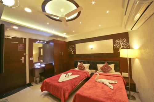 a bedroom with two beds with red sheets at Hotel Grand Pragati in Surat