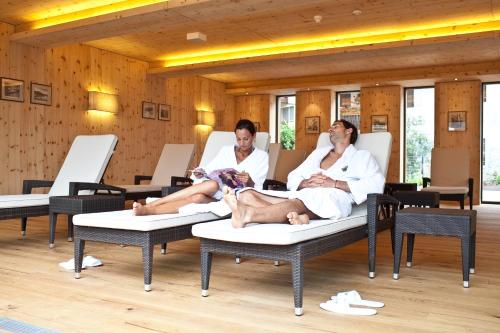 two men and a dog sitting on chairs in a spa at Hotel Grüner Baum in Bressanone