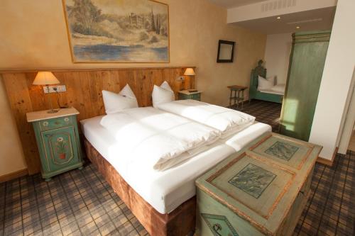 Un dormitorio con una gran cama blanca y un baño. en DIE POST Landgasthof Aufkirchen, en Berg am Starnberger See